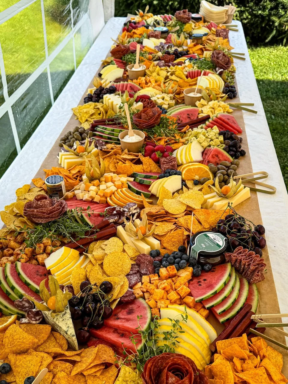 Long grazing table prepared beneath an event tent